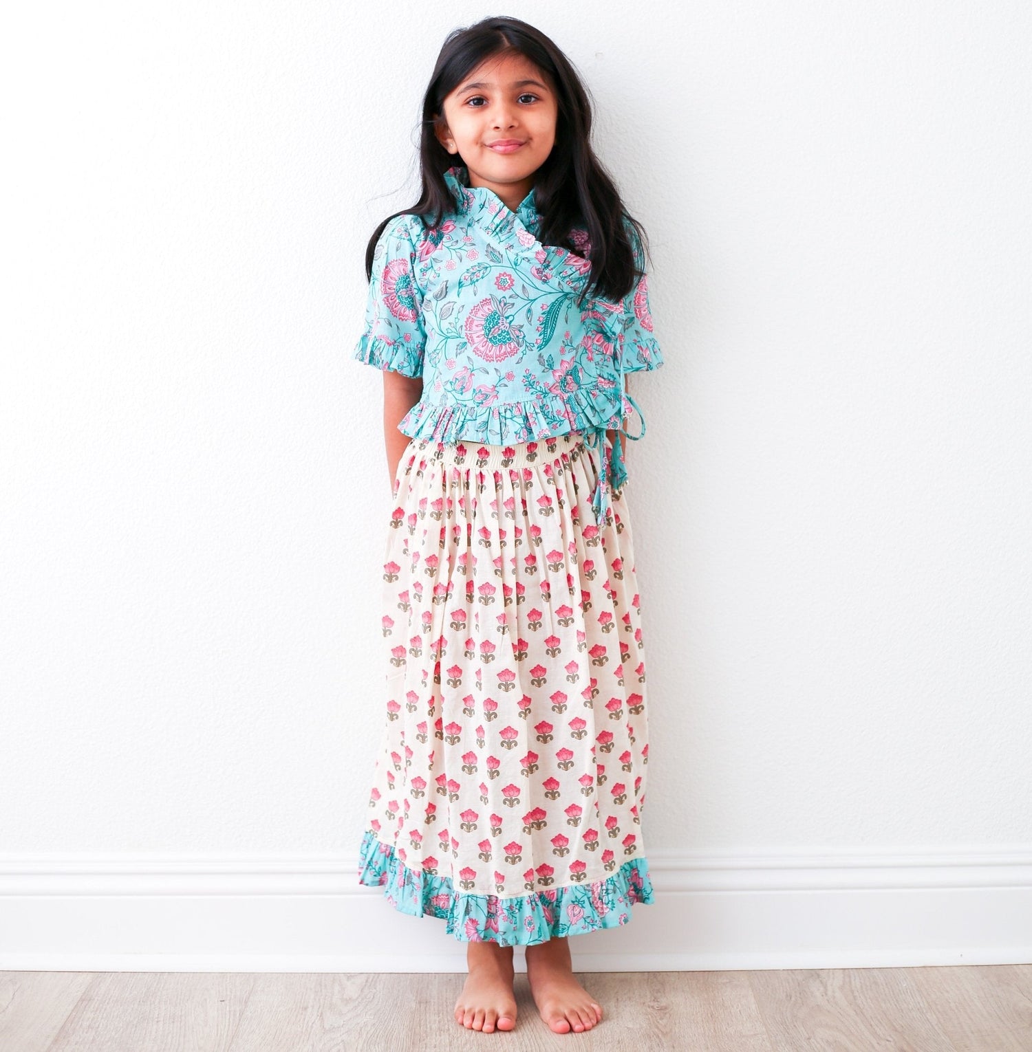 Girls lehenga in blue with colorful design and teal accents, wraparound 3/4-sleeve top and flowing skirt.