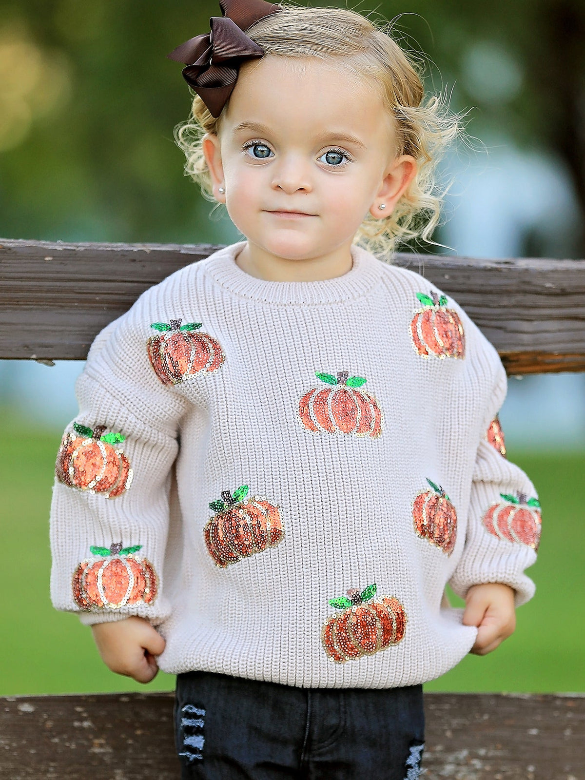 Beige sweater with a sequin pumpkin design on the front, styled for fall.