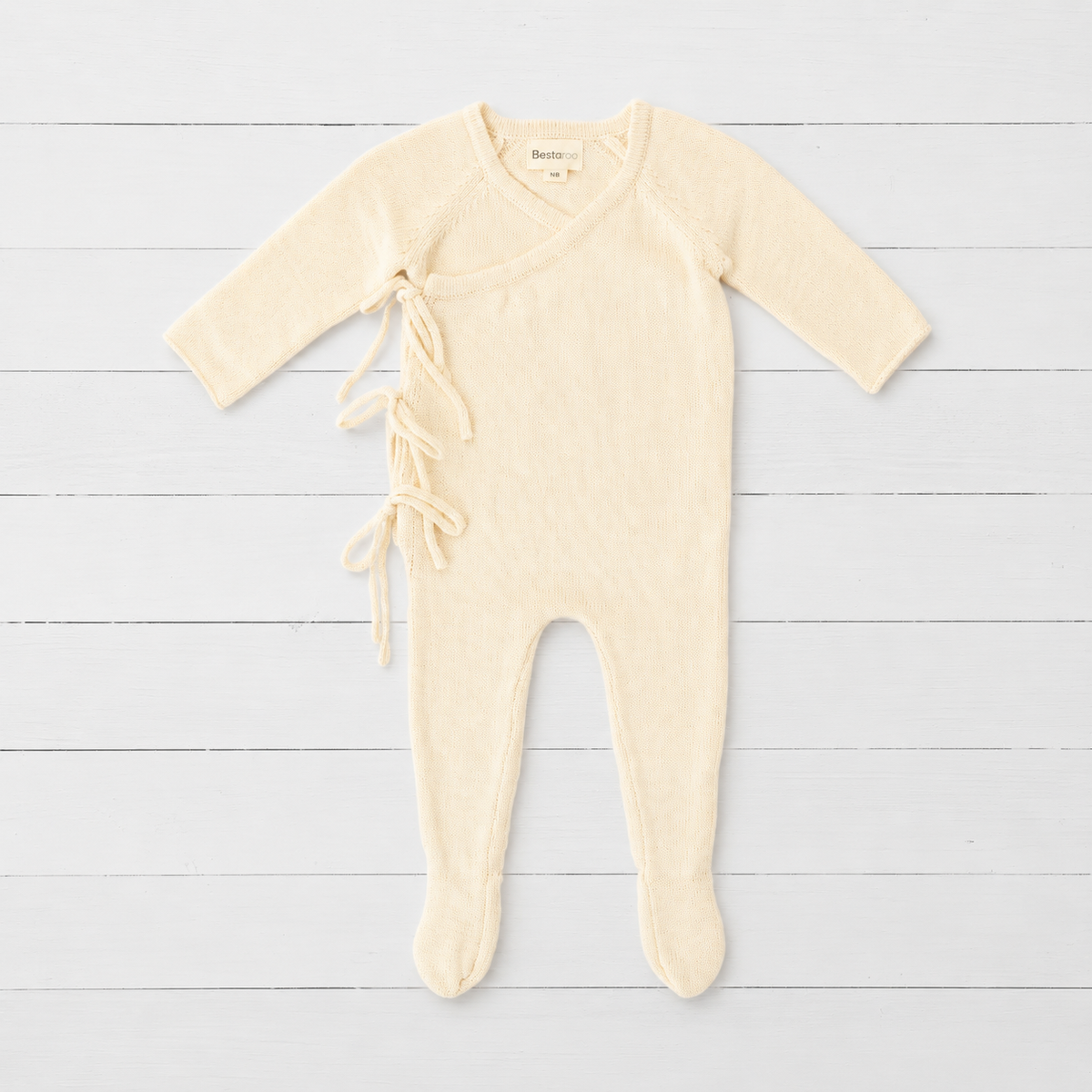 Buttercream yellow knit baby romper with wrap front, side ties, long sleeves and built-in feet