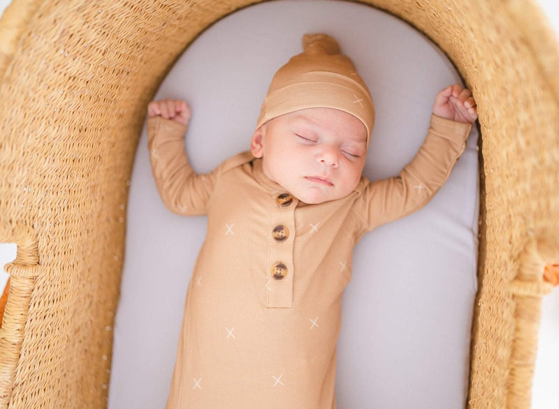Newborn in beige knot hat and matching outfit.