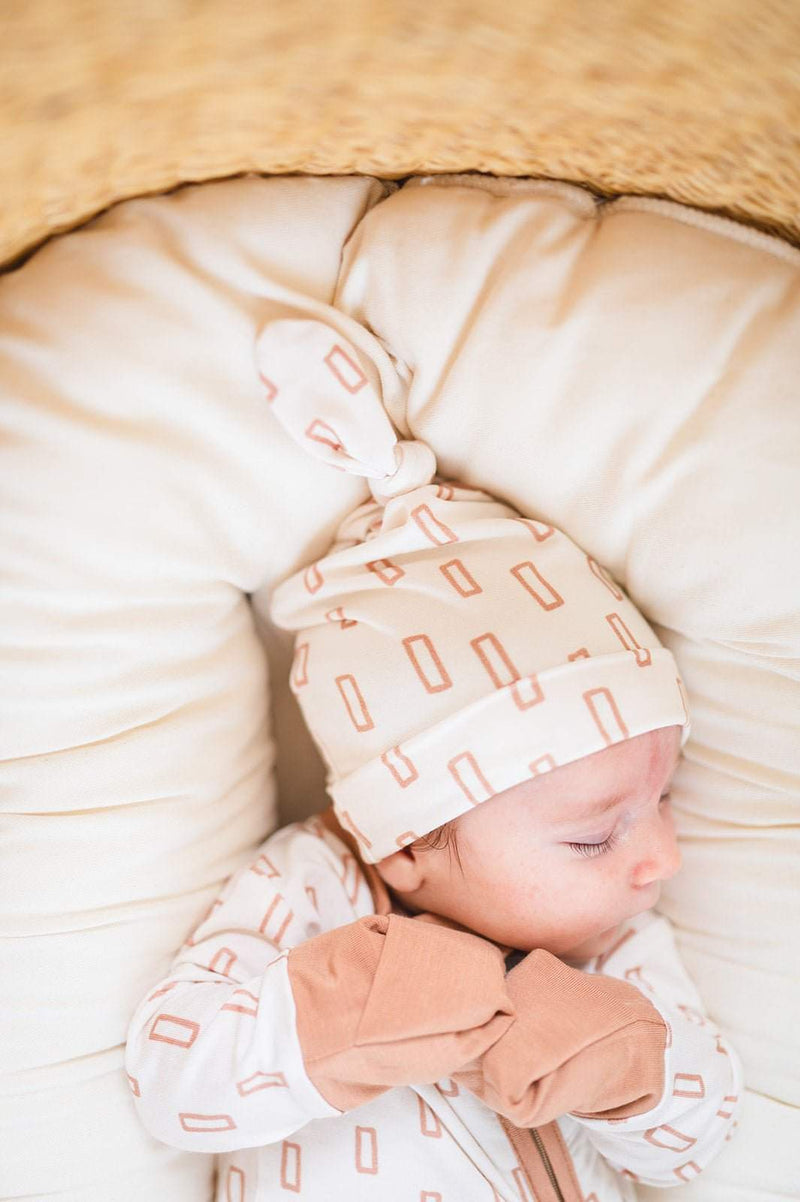 Baby wearing soft bamboo knot hat with neutral rectangle pattern.