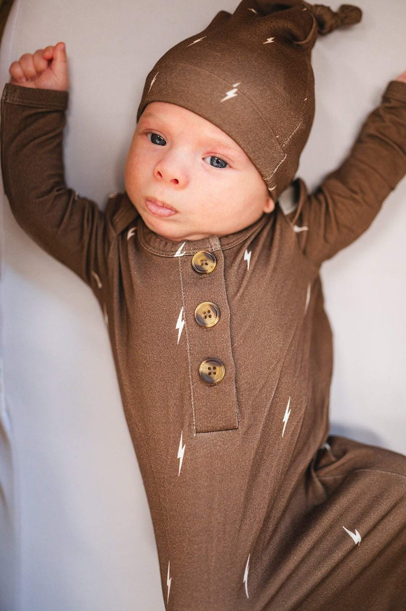 Baby wearing brown lightning knotted gown with hat, featuring bamboo fabric and fold-over cuffs.