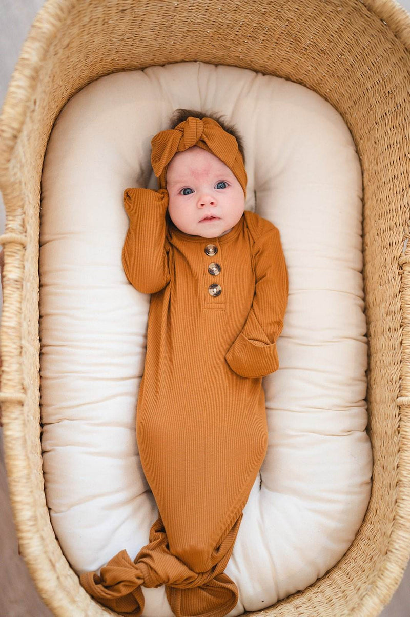 Knotted baby gown in caramel ribbed fabric with fold-over cuffs.