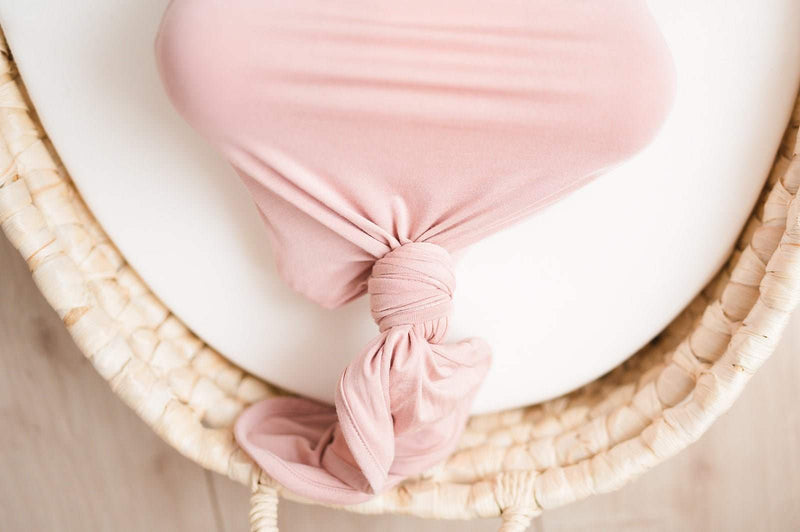 Dusty pink bamboo knotted baby gown in a basket.