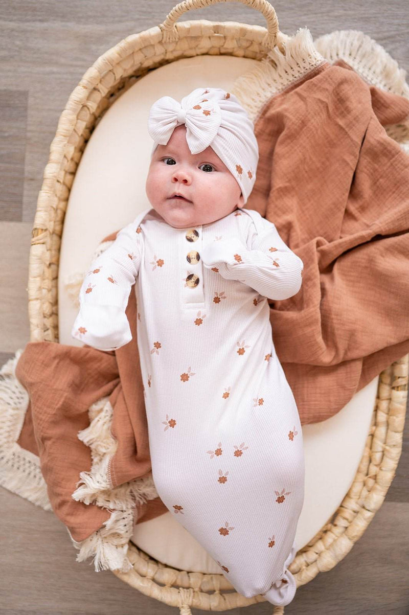 Knotted baby gown in bamboo viscose with floral print, featuring fold-over cuffs and adjustable knotted bottom.