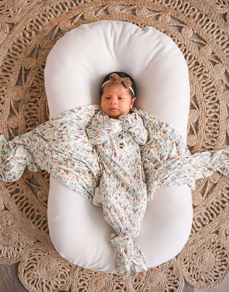 Knotted baby gown in floral bamboo viscose with fold-over cuffs for infants.