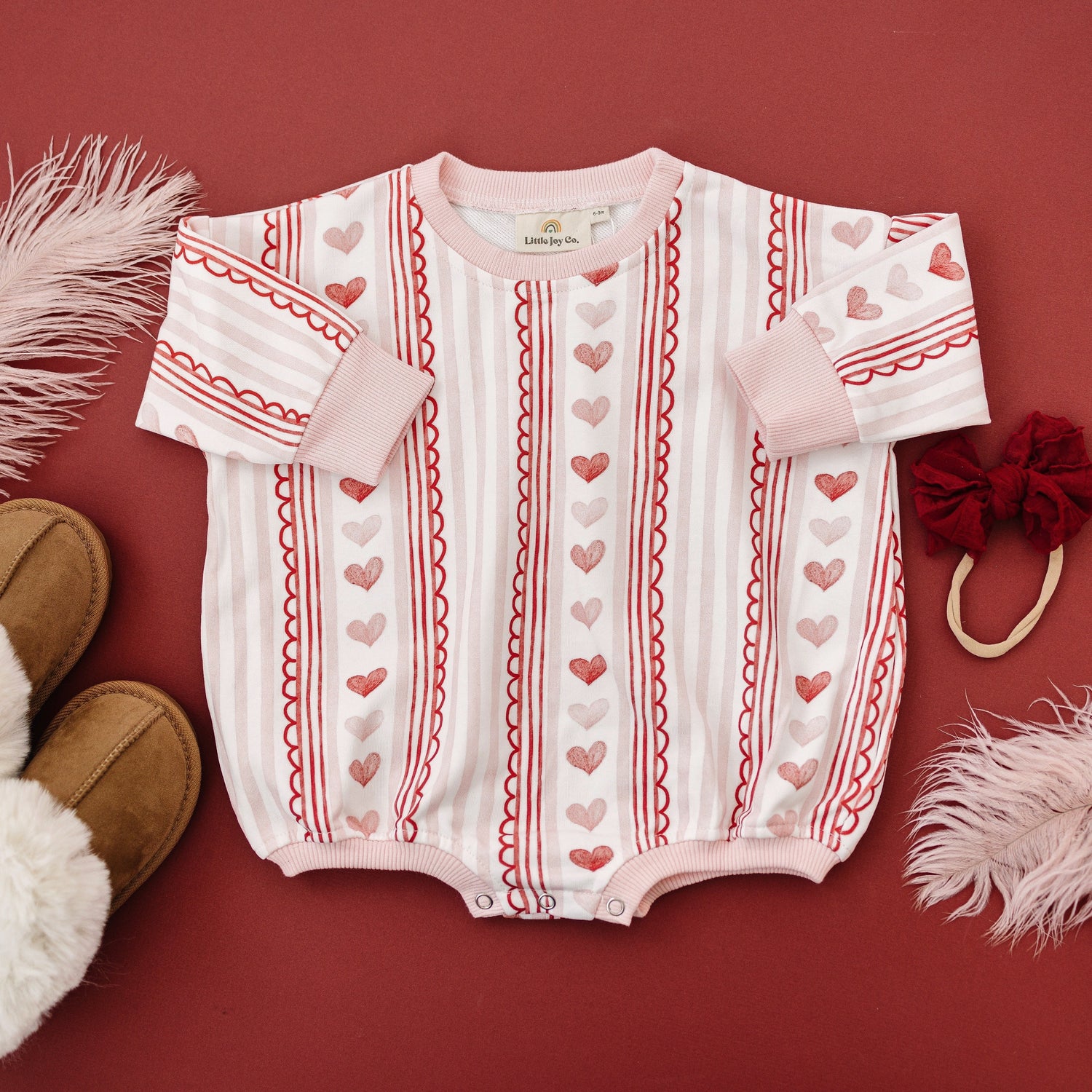Baby wearing Laced with Love organic cotton sweatshirt romper with lace trim detail, smiling.