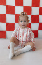 Baby wearing Laced with Love organic cotton sweatshirt romper with lace trim detail, smiling.
