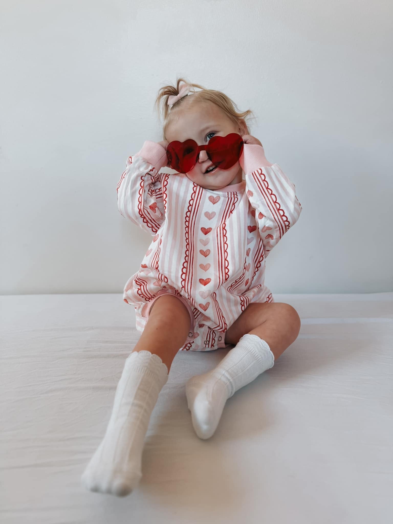 Baby wearing Laced with Love organic cotton sweatshirt romper with lace trim detail, smiling.