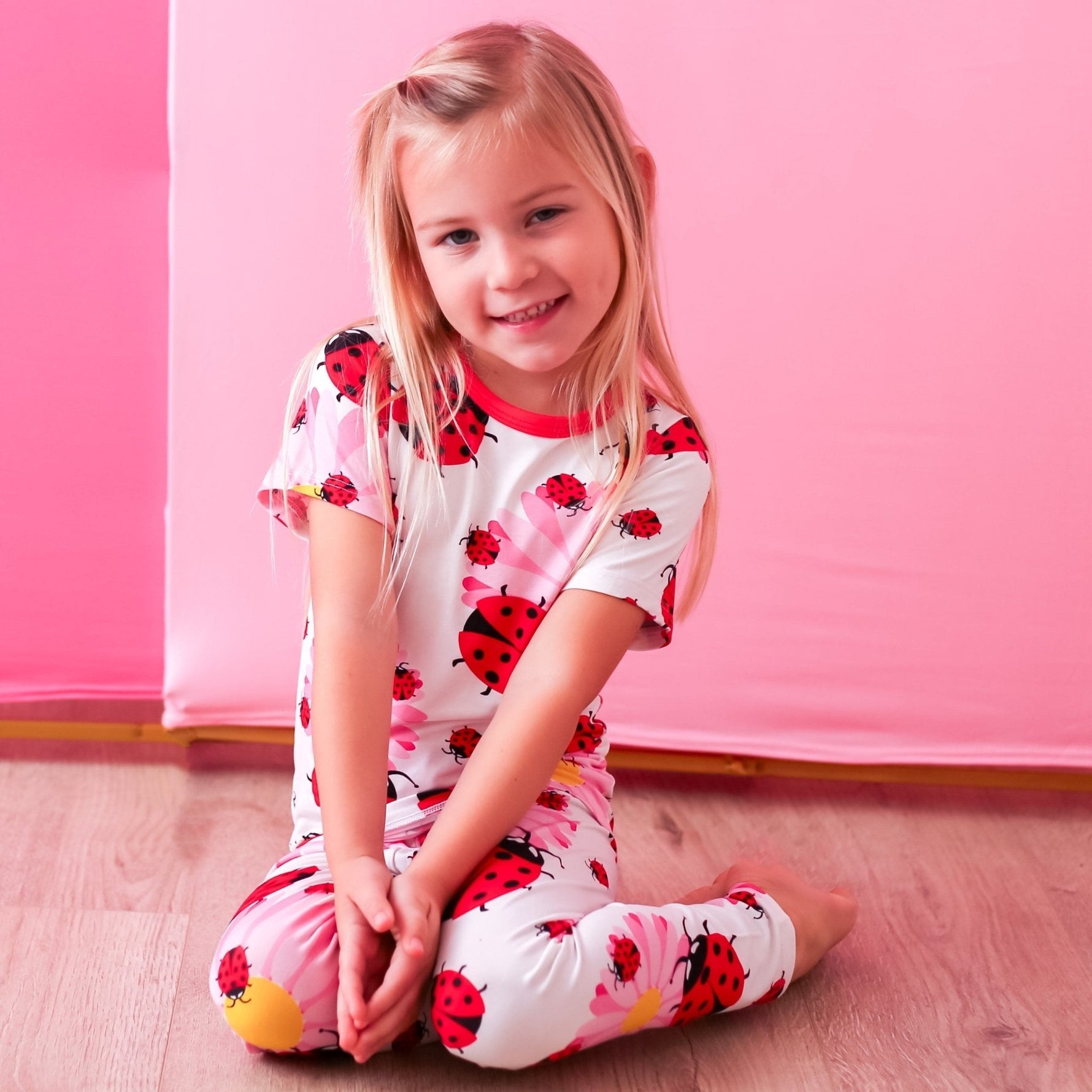 Two-piece baby pajama set with a ladybug print in red and pink, matching long-sleeve top and pants.