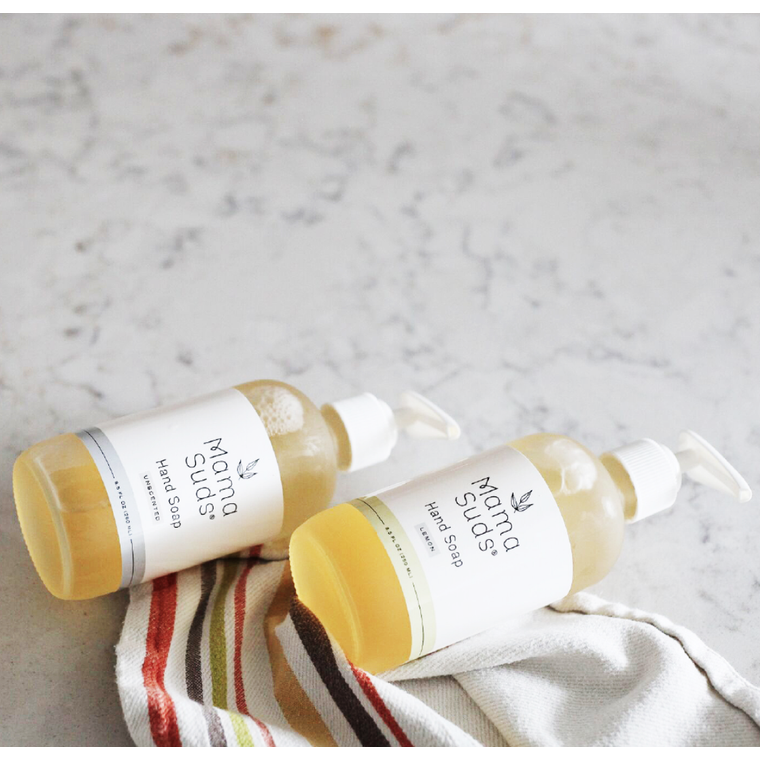 Natural hand soap bottles on marble surface with striped cloth.