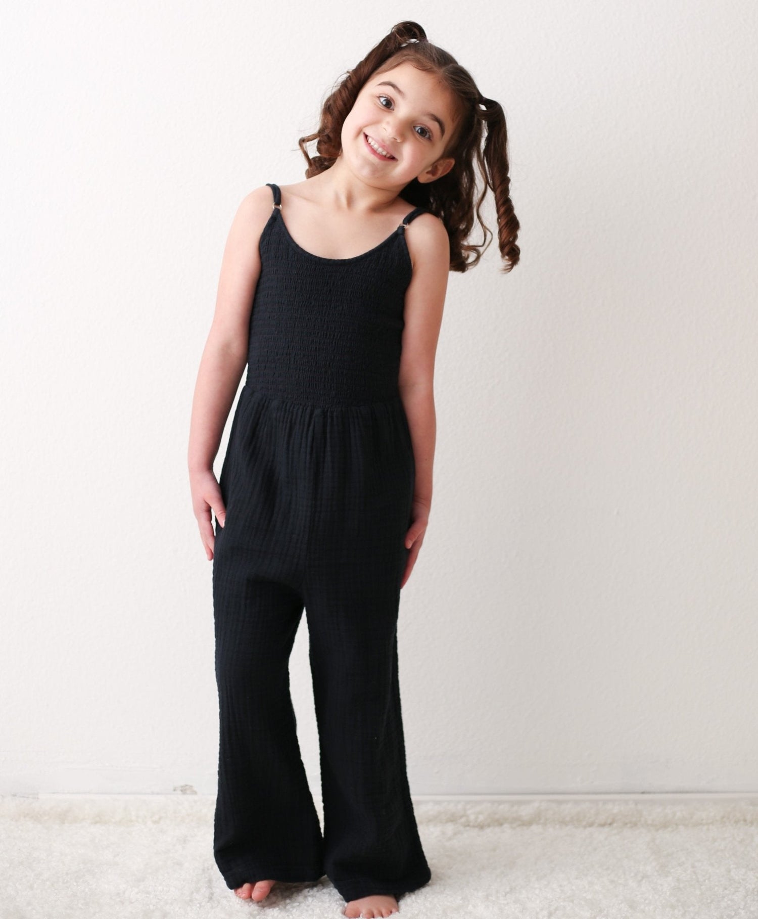Charcoal sleeveless jumpsuit with adjustable straps, smocked top, and a pocket, in soft gauze cotton.