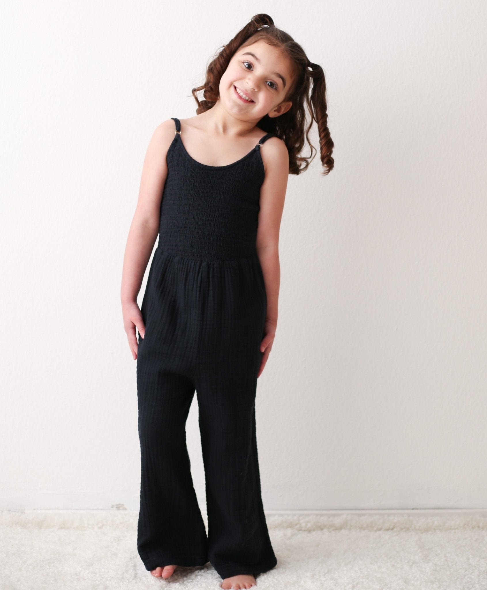 Charcoal sleeveless jumpsuit with adjustable straps, smocked top, and a pocket, in soft gauze cotton.