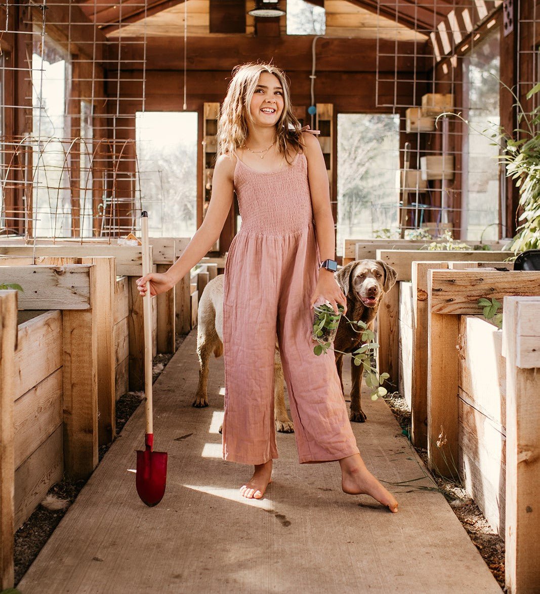Dusty rose jumpsuit with smocked top, adjustable straps, and a pocket in soft gauze fabric