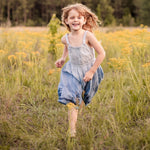 Baby girl dress in ombred blue with a modern neckline, elastic waist, and embroidery near the hem.