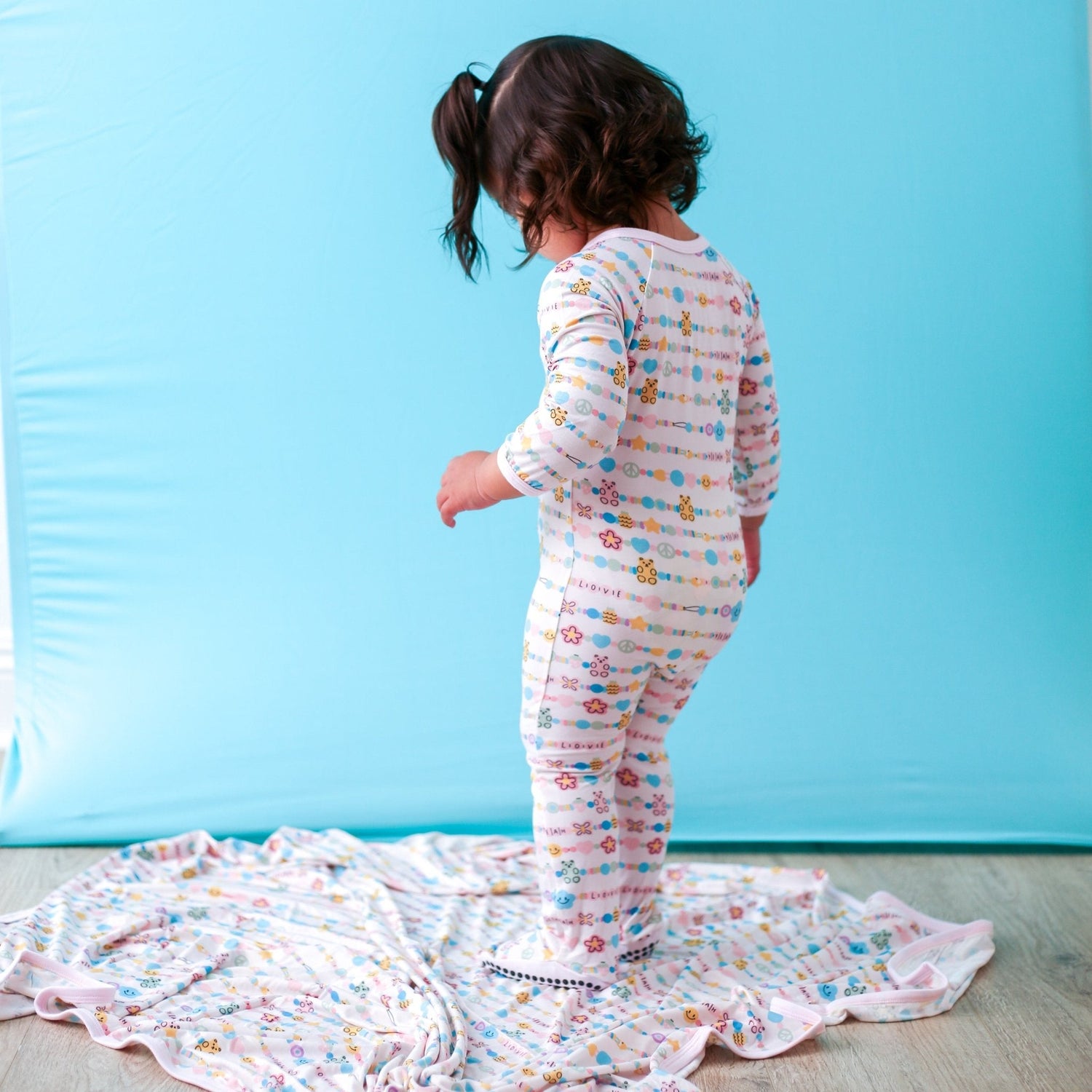 Baby footie pajamas in a friendship bracelet print with a dual zipper and fold-over hand mittens.
