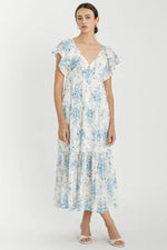 Light blue floral flutter sleeve tiered maxi dress with a long flowing skirt, worn with sandals