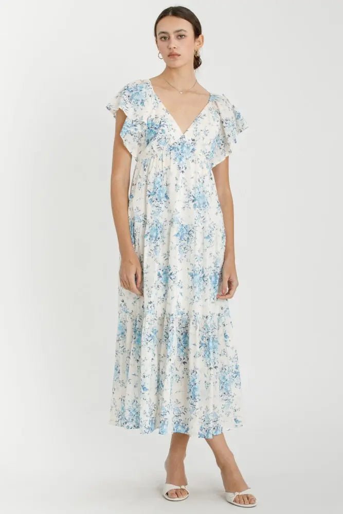 Light blue floral flutter sleeve tiered maxi dress with a long flowing skirt, worn with sandals