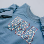 Baby wearing a cozy Little Joy Co. bamboo sweatshirt romper in a neutral color, smiling softly.