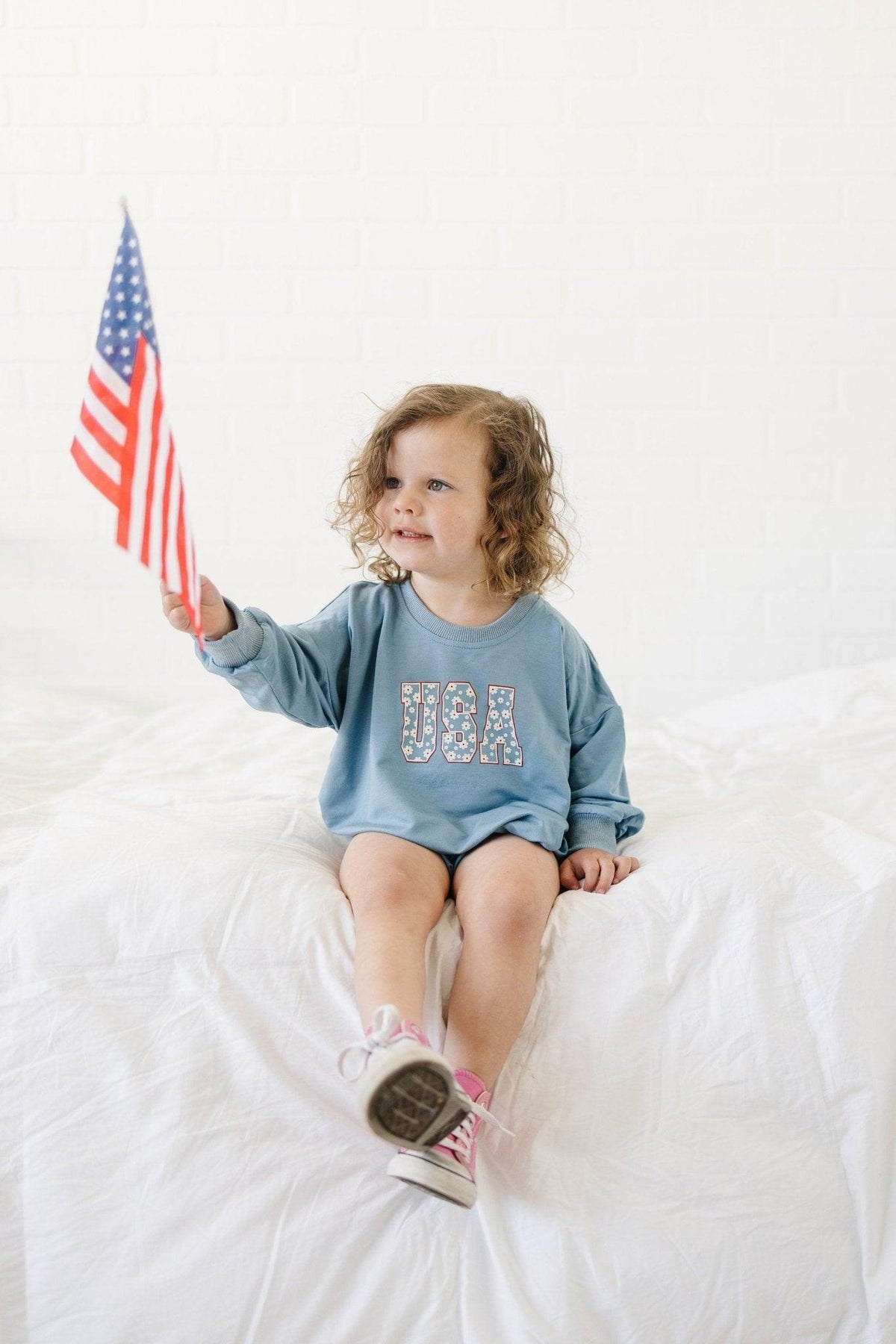 Baby wearing a cozy Little Joy Co. bamboo sweatshirt romper in a neutral color, smiling softly.