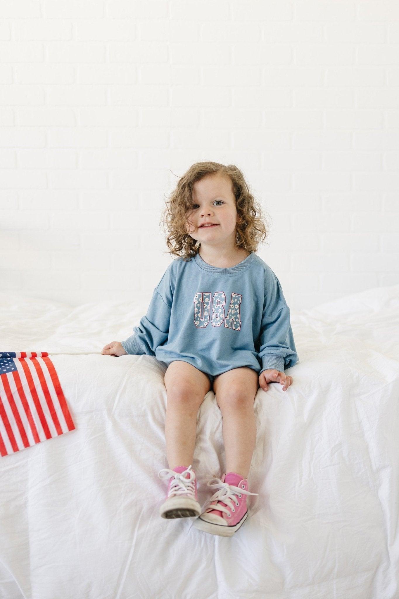 Baby wearing a cozy Little Joy Co. bamboo sweatshirt romper in a neutral color, smiling softly.