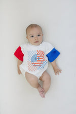 Little Joy Co. baby wearing a colorblock t-shirt romper with checkered flag and smile design