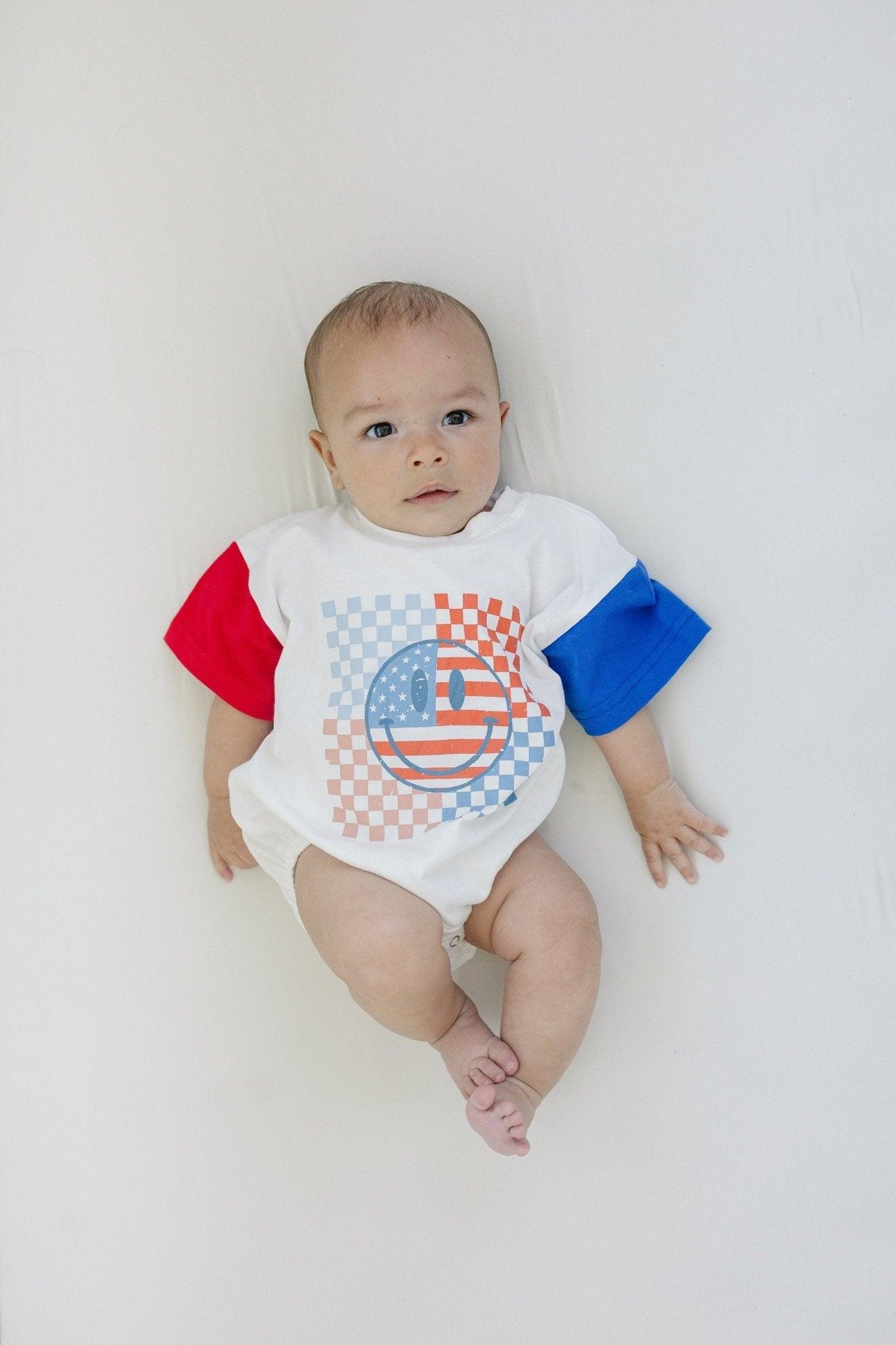 Little Joy Co. baby wearing a colorblock t-shirt romper with checkered flag and smile design