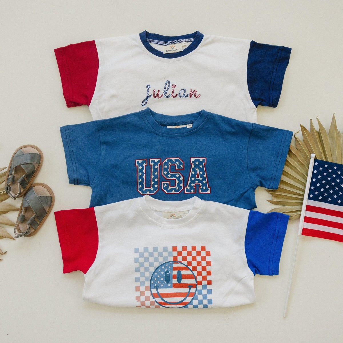 Little Joy Co. baby wearing a colorblock t-shirt romper with checkered flag and smile design