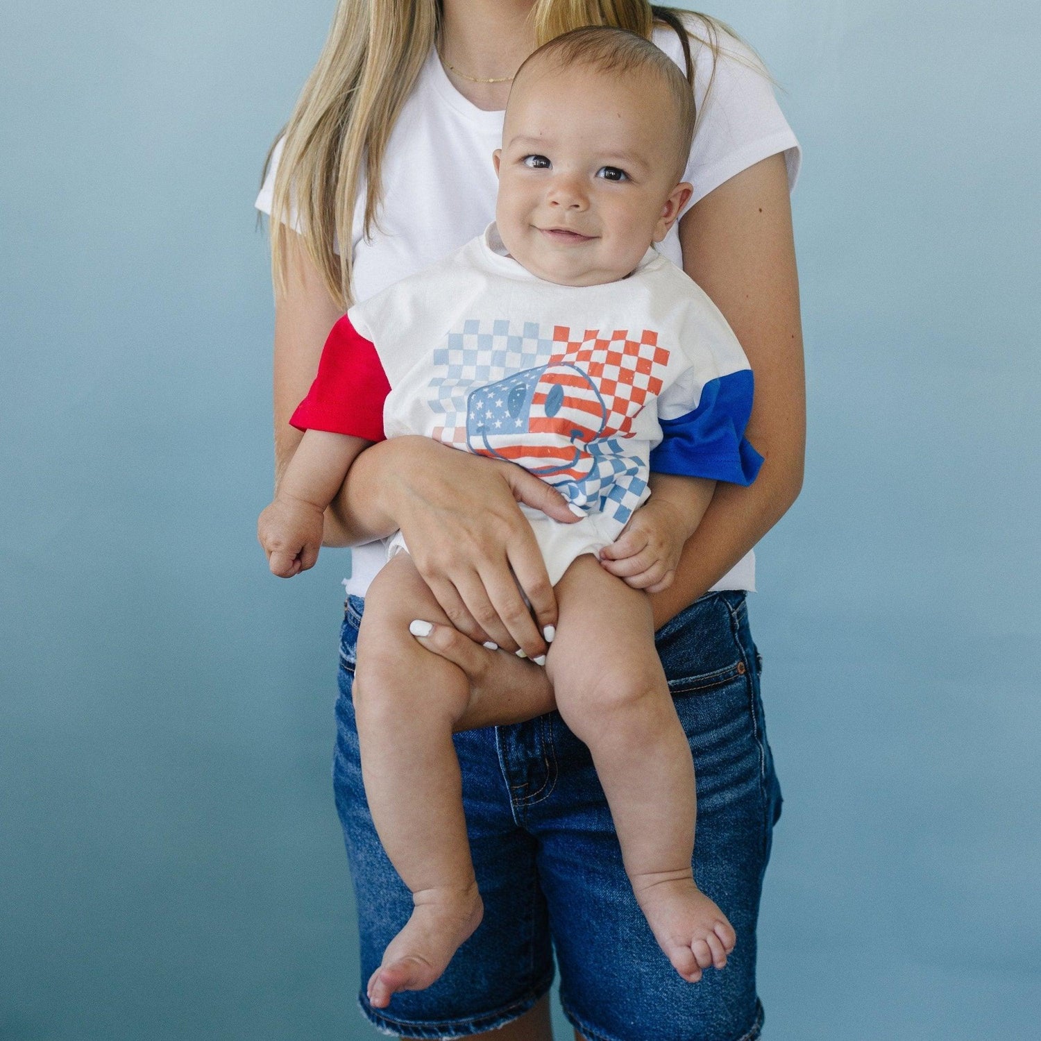 Little Joy Co. baby wearing a colorblock t-shirt romper with checkered flag and smile design