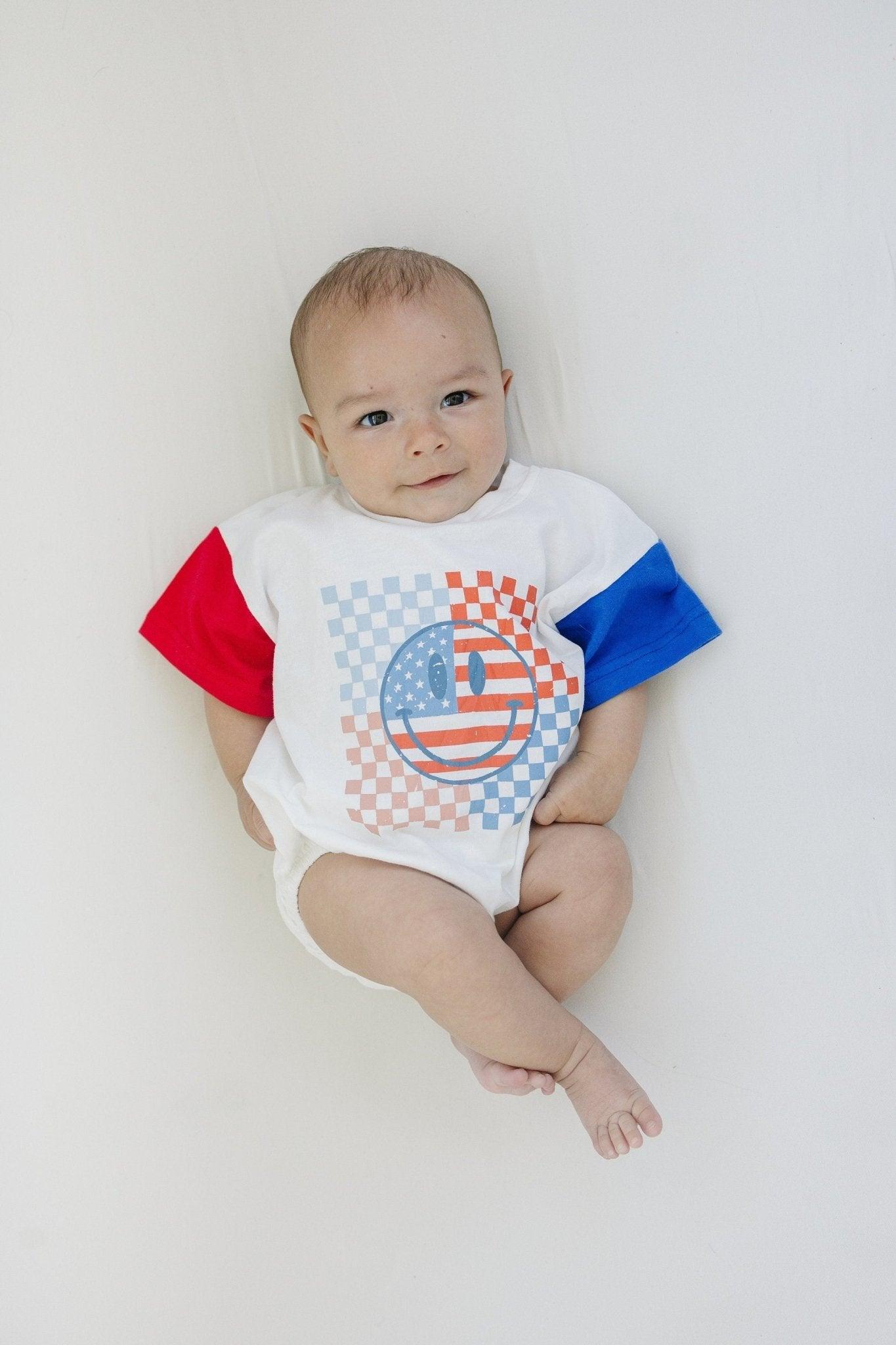 Little Joy Co. baby wearing a colorblock t-shirt romper with checkered flag and smile design