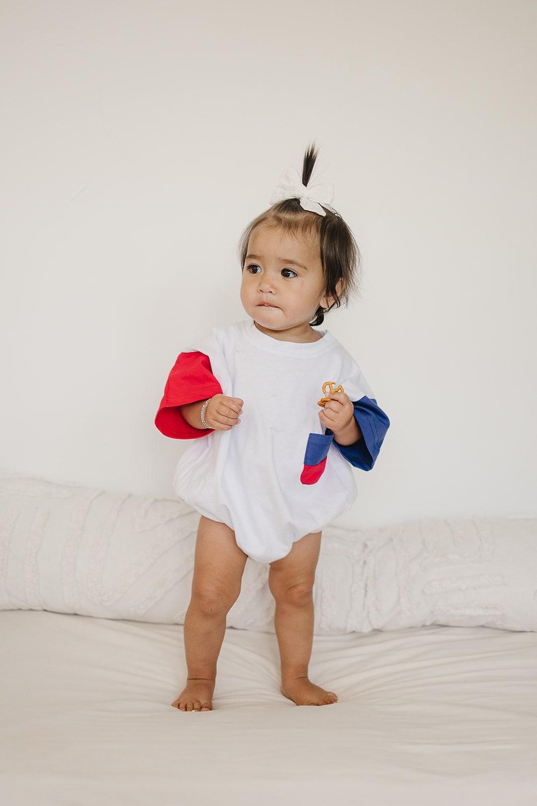 Baby wearing Little Joy Co. patriotic colorblock pocket t-shirt romper, smiling and playing.