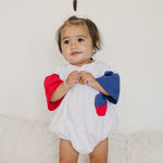 Baby wearing Little Joy Co. patriotic colorblock pocket t-shirt romper, smiling and playing.