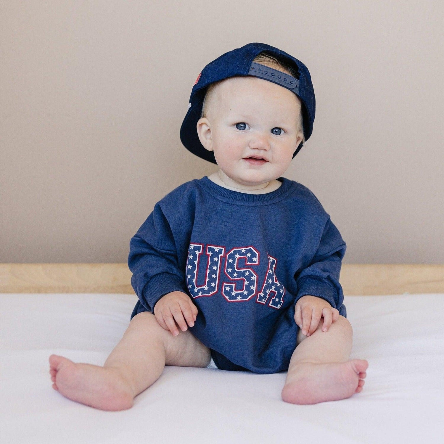 Little Joy Co. organic terry sweatshirt romper for babies, light gray, shown on a happy baby.