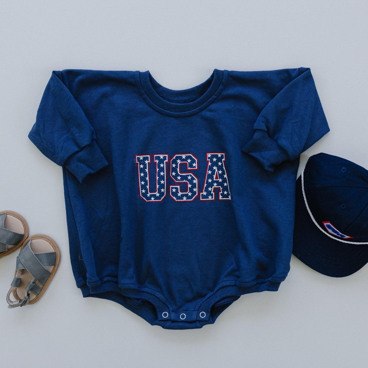 Little Joy Co. organic terry sweatshirt romper for babies, light gray, shown on a happy baby.