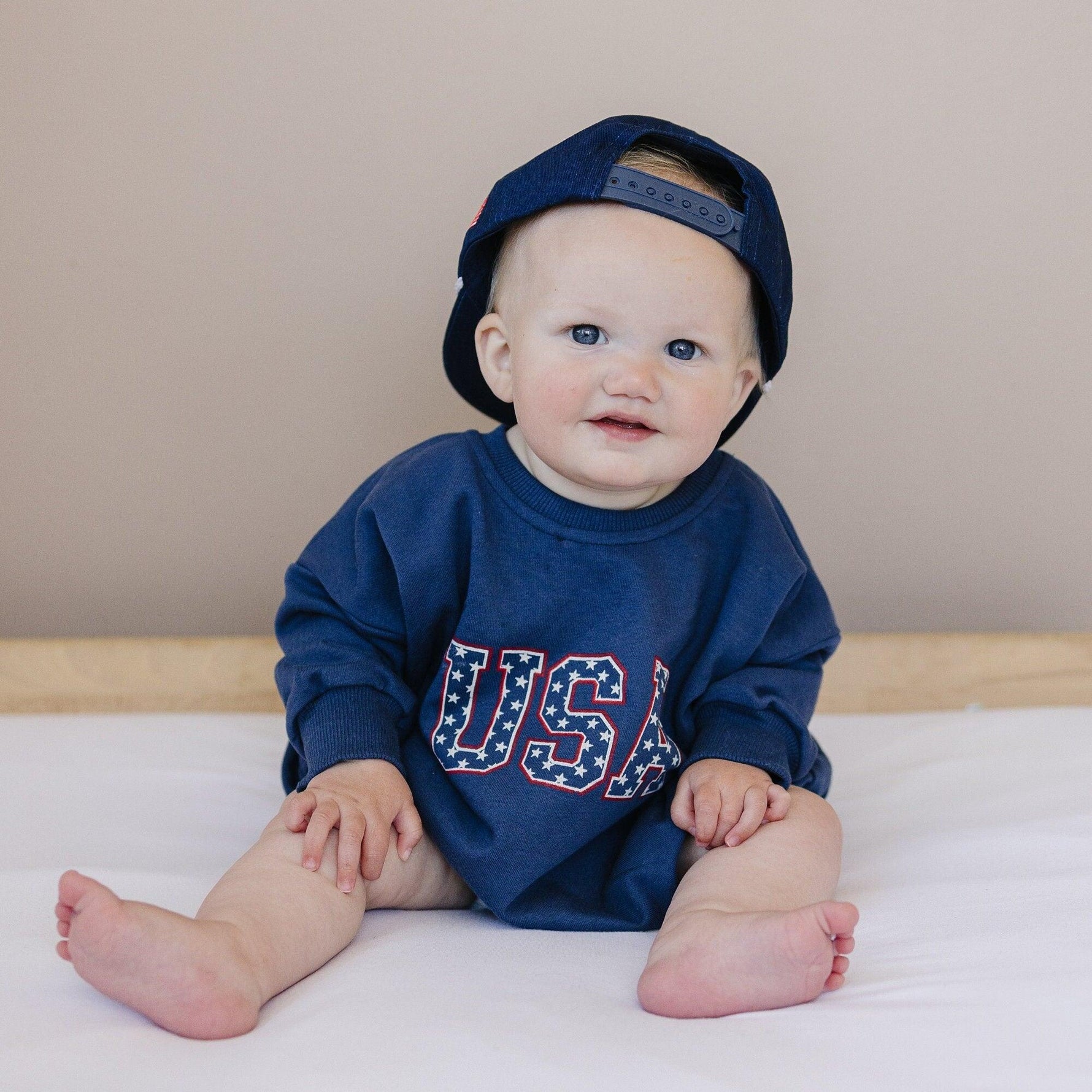 Little Joy Co. organic terry sweatshirt romper for babies, light gray, shown on a happy baby.