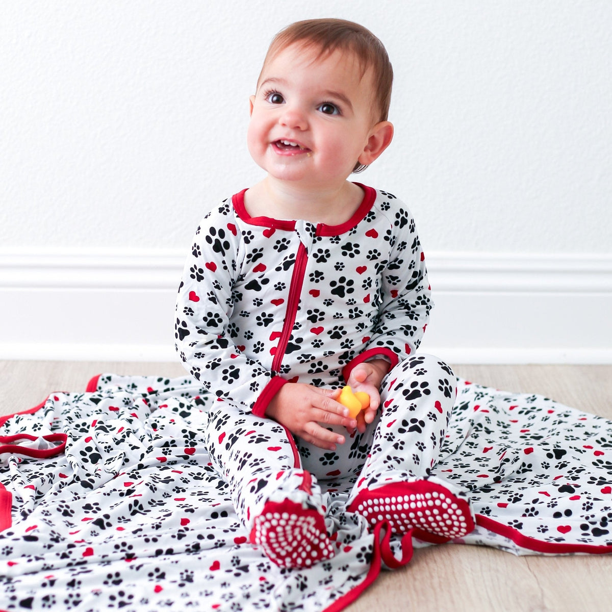 Pink footie pajamas with a puppy paw and heart print, fold-over hand mittens, and a full-length zipper.