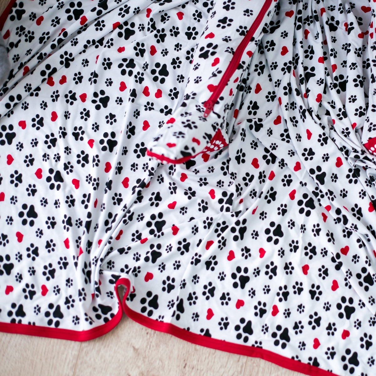 Swaddle blanket with pink and red puppy paw and polka dot pattern spread flat