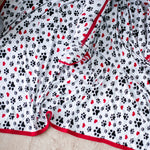 Swaddle blanket with pink and red puppy paw and polka dot pattern spread flat