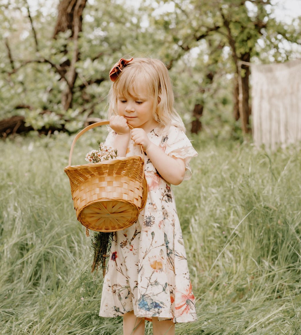 Cream dress with painted floral print, elastic waist, and lace trim at the arm openings.