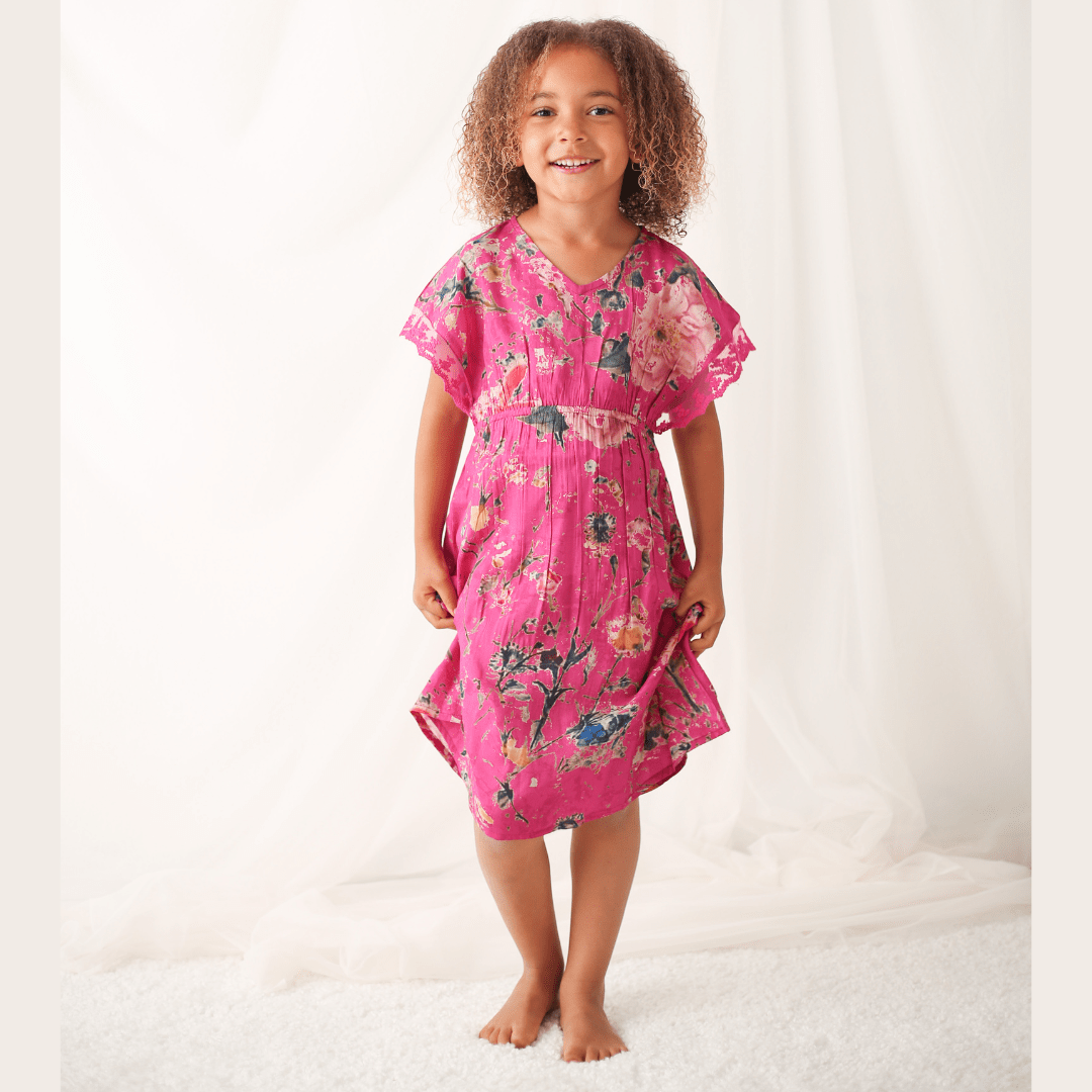 Hot pink dress with painted floral pattern and lace trim at the arms, worn by a child with sandals.