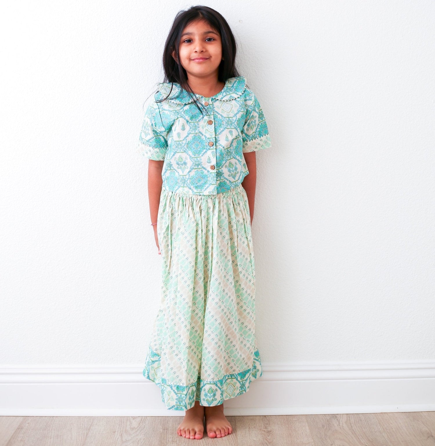Teal and cream baby girl lehenga with ethnic floral pattern, a collar with wooden buttons, and matching skirt