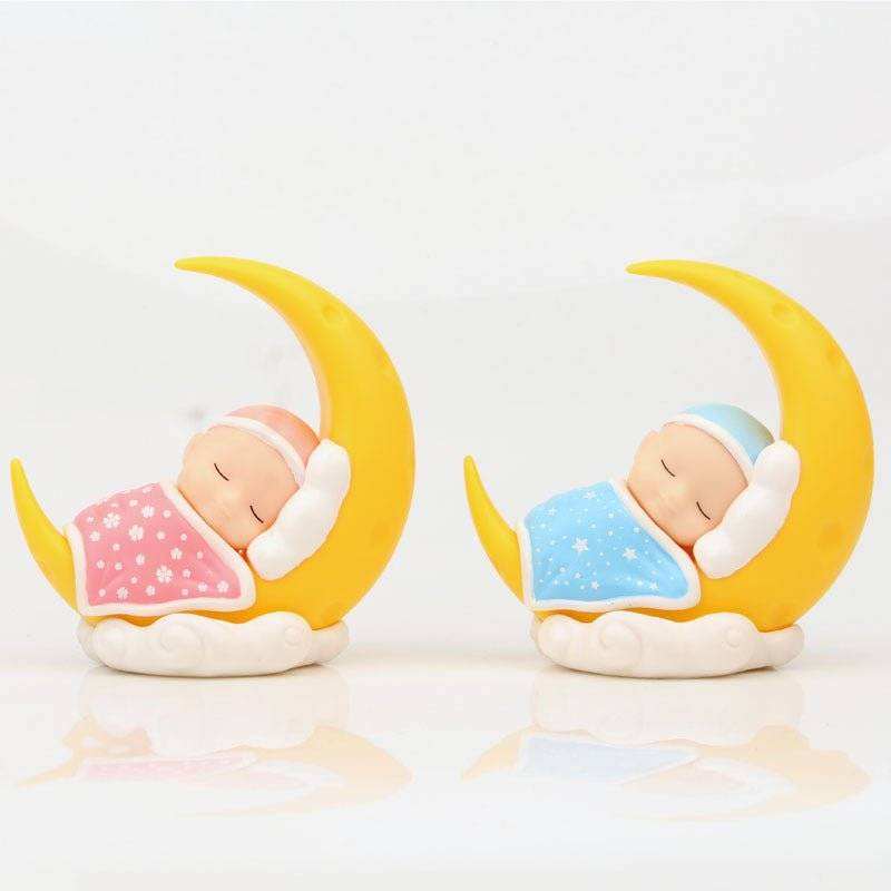 Micro-view Moon Decoration with sleeping baby in pink and blue quilts on crescent moons.