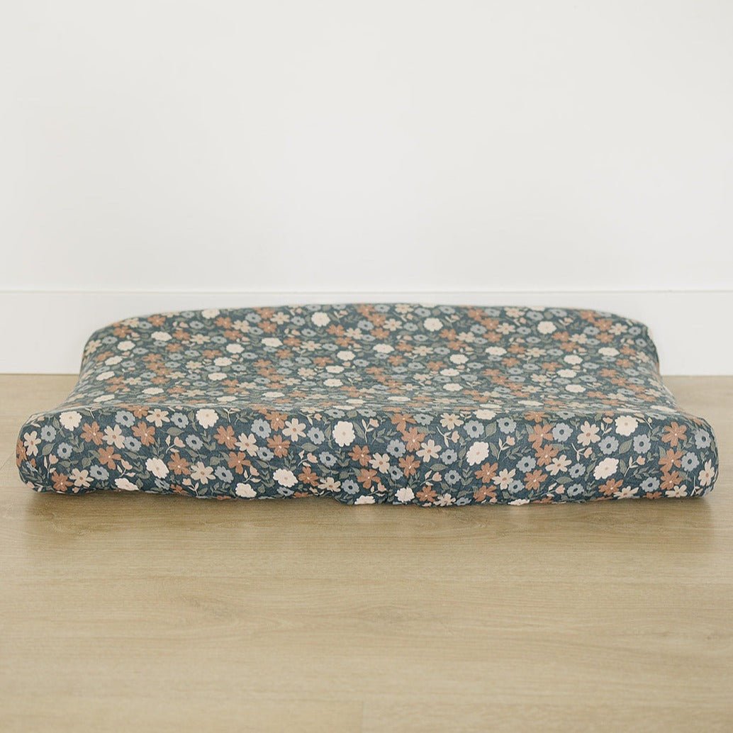Muslin changing pad cover with a dark midnight floral pattern fitted over a standard changing pad