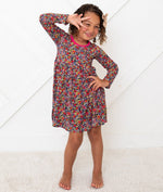Toddler wearing a long sleeve floral petal print dress in dark and pink tones
