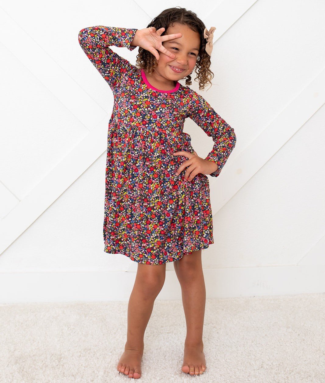 Toddler wearing a long sleeve floral petal print dress in dark and pink tones