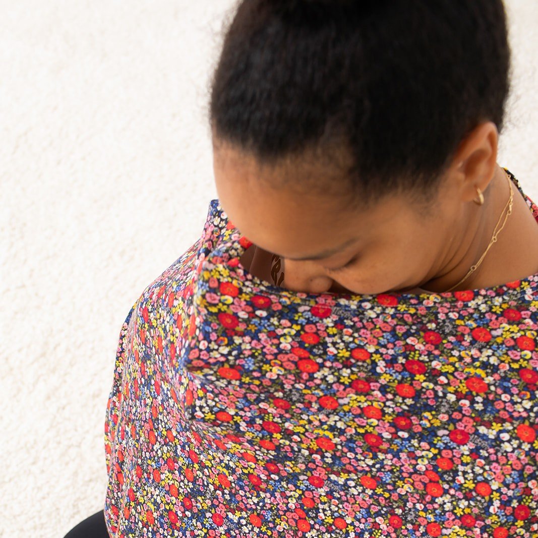 Nursing cover in dark midnight floral print with a round neckline, shown with matching zippered pouch.