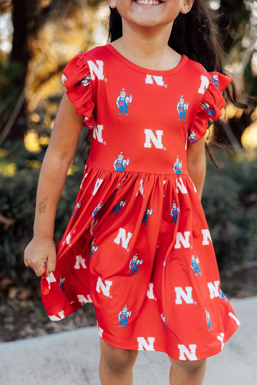 Red flutter-sleeve twirl dress featuring Herbie Husker and Nebraska Cornhusker graphics.