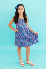 Sleeveless dress with a fish-in-the-sea print, shoulder ruffle, and straps that criss-cross in back.