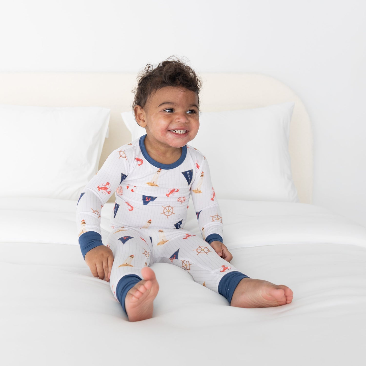 Toddler two-piece pajamas in a nautical print with sailboats, lighthouses, lobster flags, and ship wheels