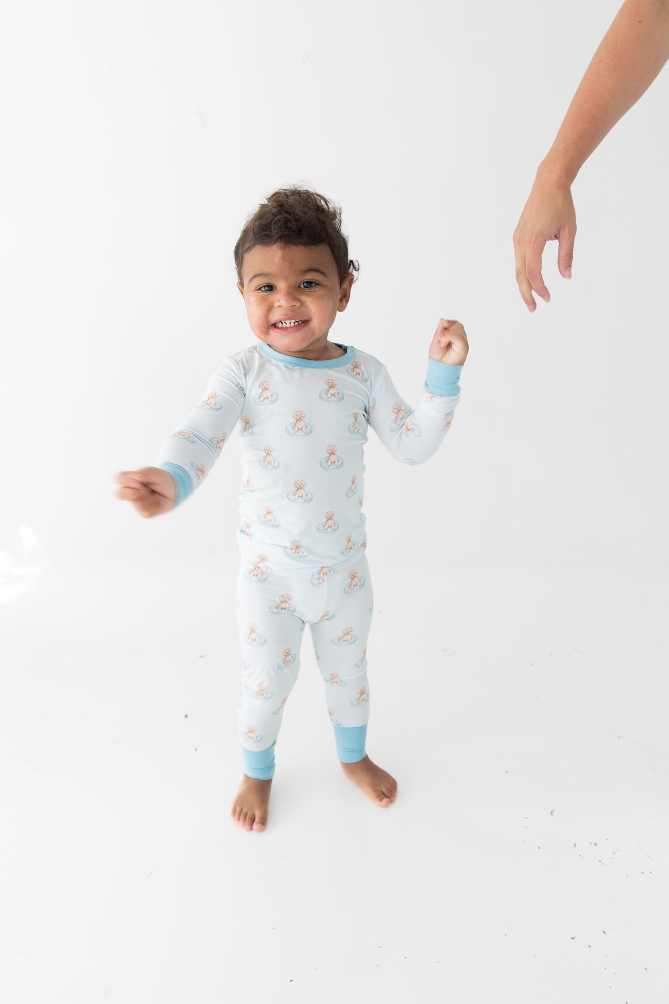 Toddler pajama set with a print of puppies floating in small blue pools on a light background